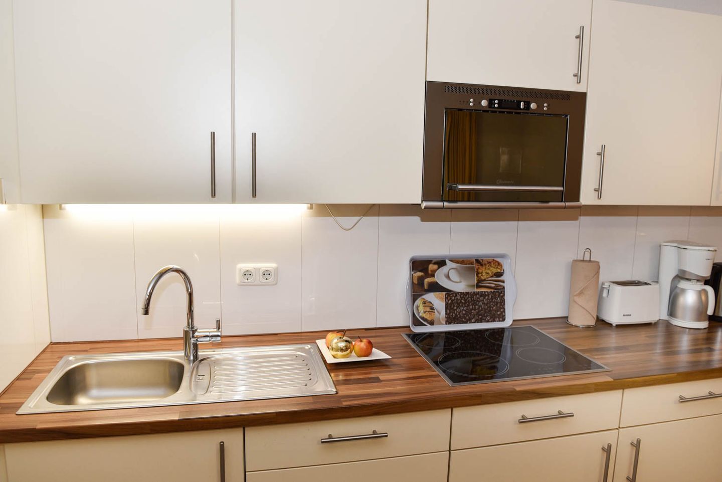 A modern kitchen with a stainless steel sink, a built-in oven, and a wooden countertop.