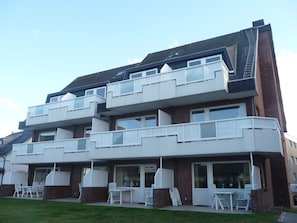 Ein mehrstöckiges Wohngebäude mit Balkonen, einer Terrasse mit Sitzgelegenheiten und einer Ziegelaußenwand.