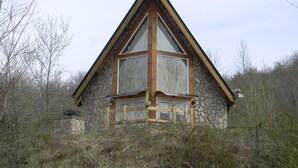 Una cabaña de piedra con techo triangular, ventanas grandes y base de piedra.