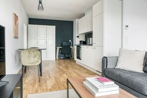A compact living space with a kitchenette, a dining area, and a seating area with a sofa and a table.