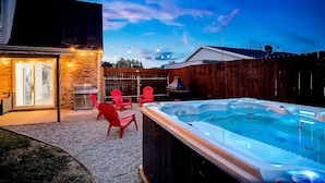 Un jardin avec un jacuzzi, un espace salon extérieur et une clôture en bois.