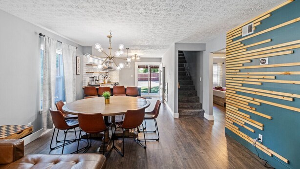 Un espace repas moderne avec une table ronde en bois, des chaises en cuir et un lustre.