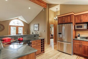 Une cuisine spacieuse dotée d’un grand îlot central, de meubles en bois et d’un réfrigérateur en acier inoxydable.
