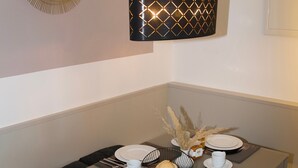Un comedor con una mesa dispuesta para cuatro, con platos, cubiertos y un vaso de jugo de naranja.