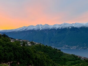 Un paisaje montañoso con picos nevados, un lago y un conjunto de edificios en una ladera.