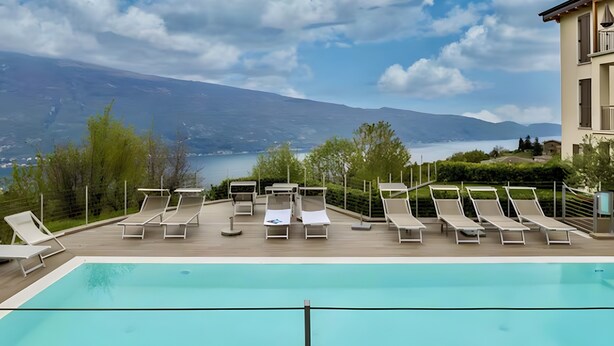 Una piscina con sillones de descanso y vistas a un lago y montañas.