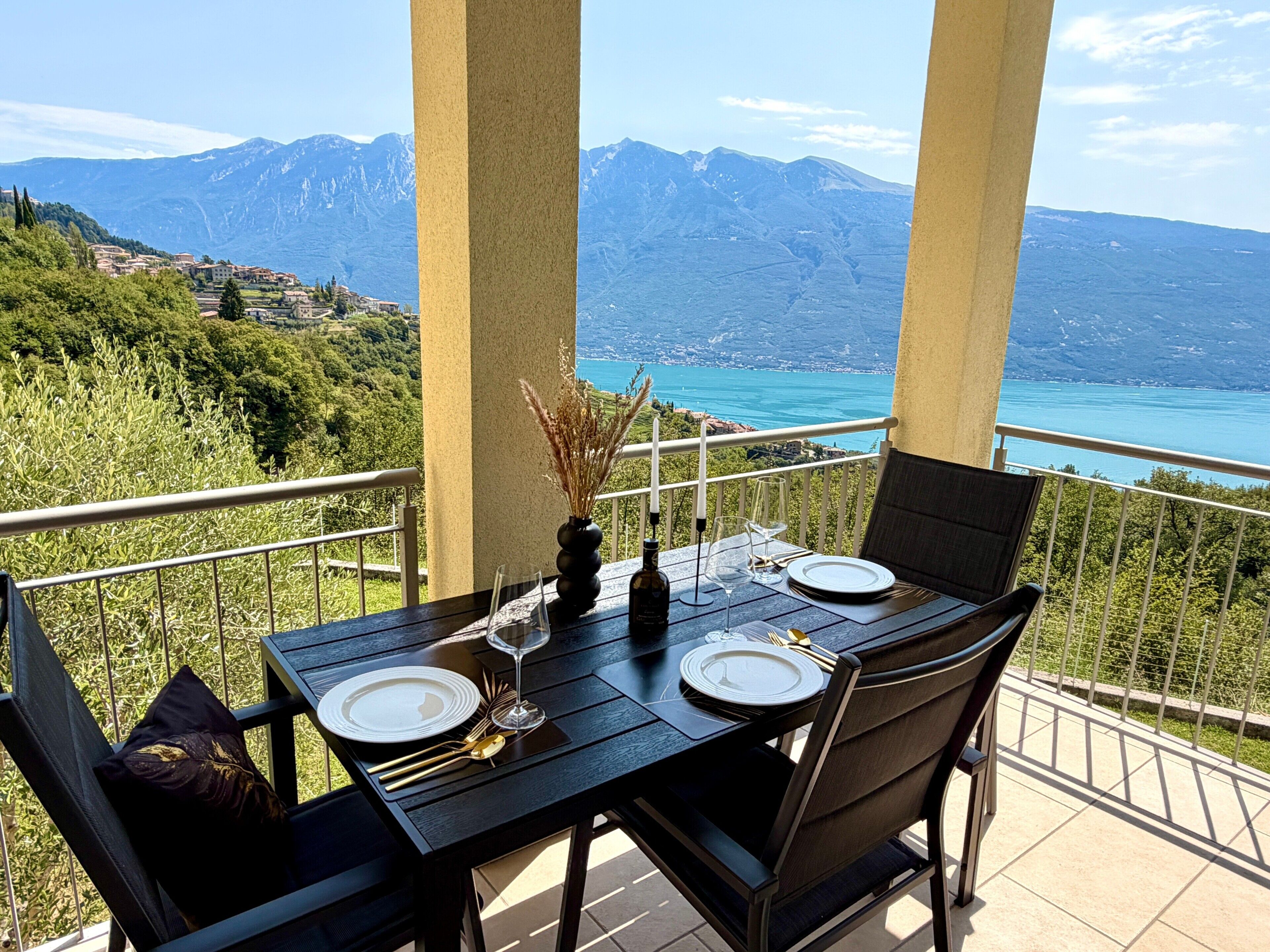 A dining table set for two with a view of mountains and a lake.