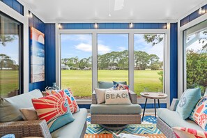 A sunroom with large windows, wicker furniture, and colorful cushions. - "Hidden Gem" - Golf Cart Fun with 5-Star Hosts! (Miramar Beach)