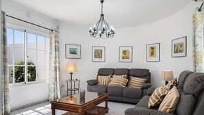 A living room with a sofa, a coffee table, a chandelier, and framed artwork on the wall. - Villa Sheila – Family Villa with Heated Pool in Puerto del Carmen (Puerto del Carmen)