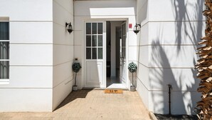 A white building with a door, potted plants, and a doormat. - Villa Sheila – Family Villa with Heated Pool in Puerto del Carmen (Puerto del Carmen)