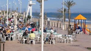 A beachside café with outdoor seating, a playground, and a view of the ocean. - Cosy Bright & Neat Apartment with Sea View, Shared Pool & Wi-Fi (Guardamar del Segura)