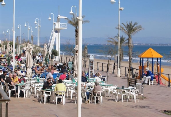 Un café situé en bord de mer, avec une terrasse, une aire de jeux et une vue sur l’océan.