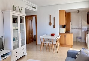 Un espace de vie compact comprenant un coin repas, une kitchenette et un téléviseur.