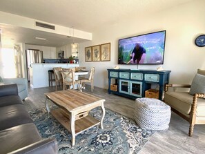 Un salon comprenant un canapé, une table basse, un téléviseur et un coin repas avec des chaises et une table.