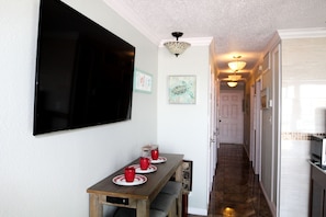 A dining area with a wooden table, red cups, and a flat-screen TV mounted on the wall. - Front row beach view at Casa Del Mar (Galveston)