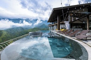 An infinity pool with a view of mountains, lounge chairs, and a restaurant area with outdoor seating. - Sapa Cat Cat Hills Resort & Spa (Sa Pa)