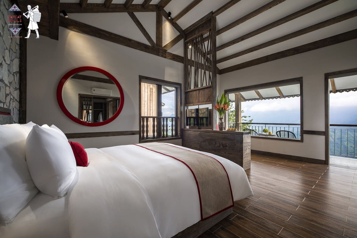 Un dormitorio con una cama grande, un espejo circular y vistas al exterior.