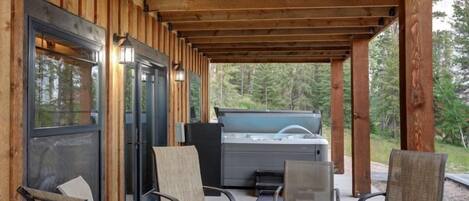 An outdoor patio with wooden beams, a hot tub, and seating.