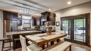 A modern kitchen with dark wood cabinets, stainless steel appliances, and a large island with a wooden table and chairs. - Dream Catcher- Spacious Rooms & Views- Sleeps 18 (North Lawrence)