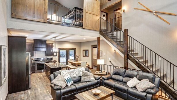 A spacious living area with a high ceiling, a staircase, and a kitchen in the background. - Dream Catcher- Spacious Rooms & Views- Sleeps 18 (North Lawrence)