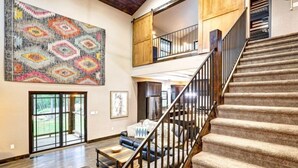 A spacious living area with a large rug, a staircase, and a view of the outdoors. - Dream Catcher- Spacious Rooms & Views- Sleeps 18 (North Lawrence)