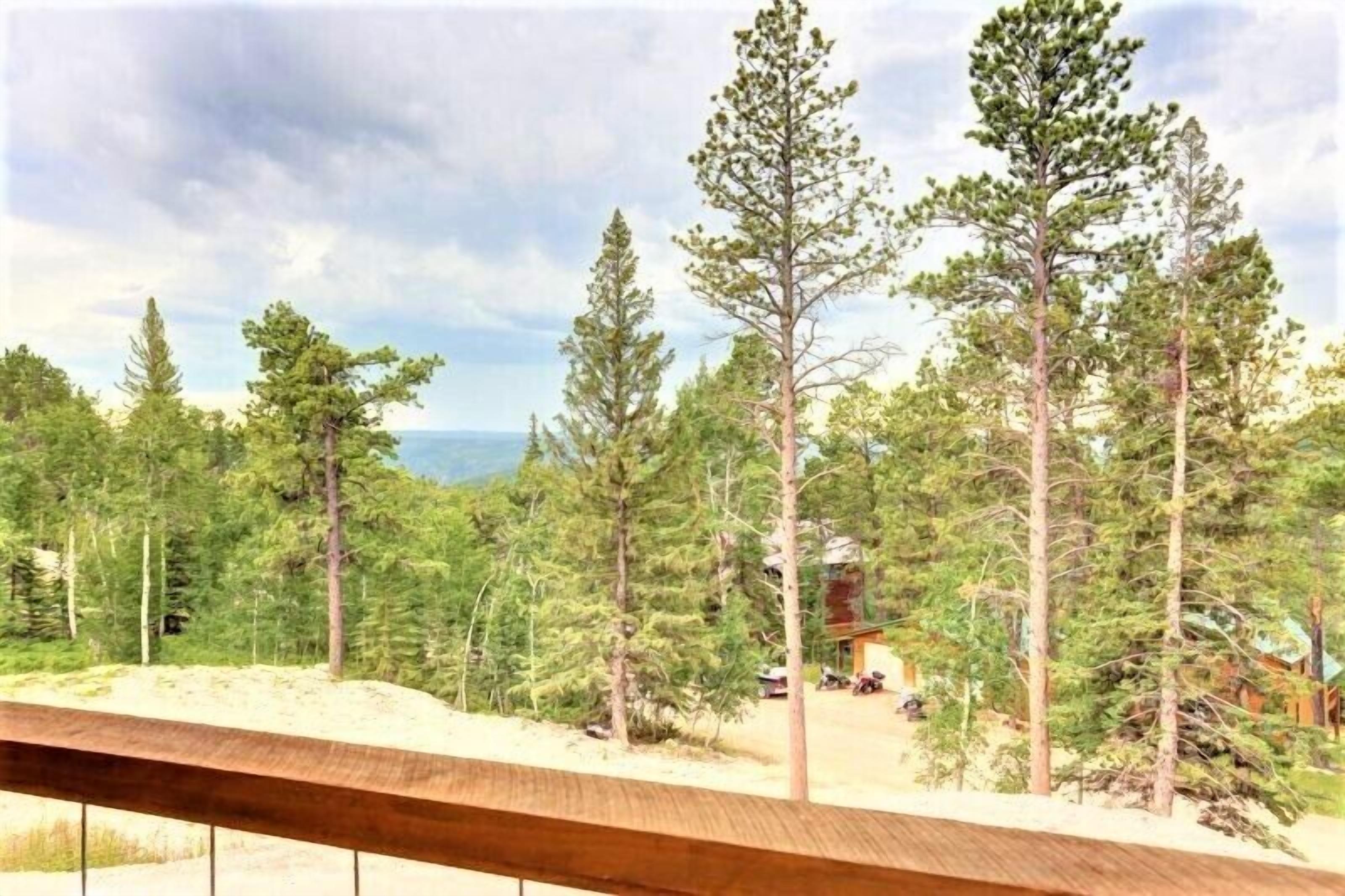 Ett skogbeklätt landskap med en stuga och en fri utsikt över bergen i fjärran.