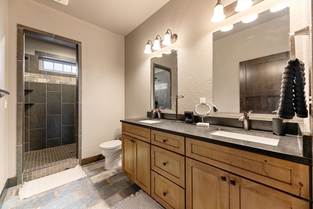 A bathroom with a shower, toilet, vanity with a sink, and a mirror.