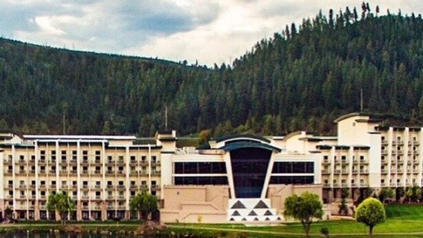 Un hotel con un diseño arquitectónico moderno, que presenta un edificio central con una estructura de techo singular y varios balcones.