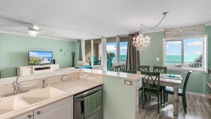 Una cocina con una isla grande, un comedor con vistas al océano y un ventilador de techo.