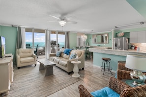 A spacious living room with a beige sofa, a coffee table, and a view of the ocean.