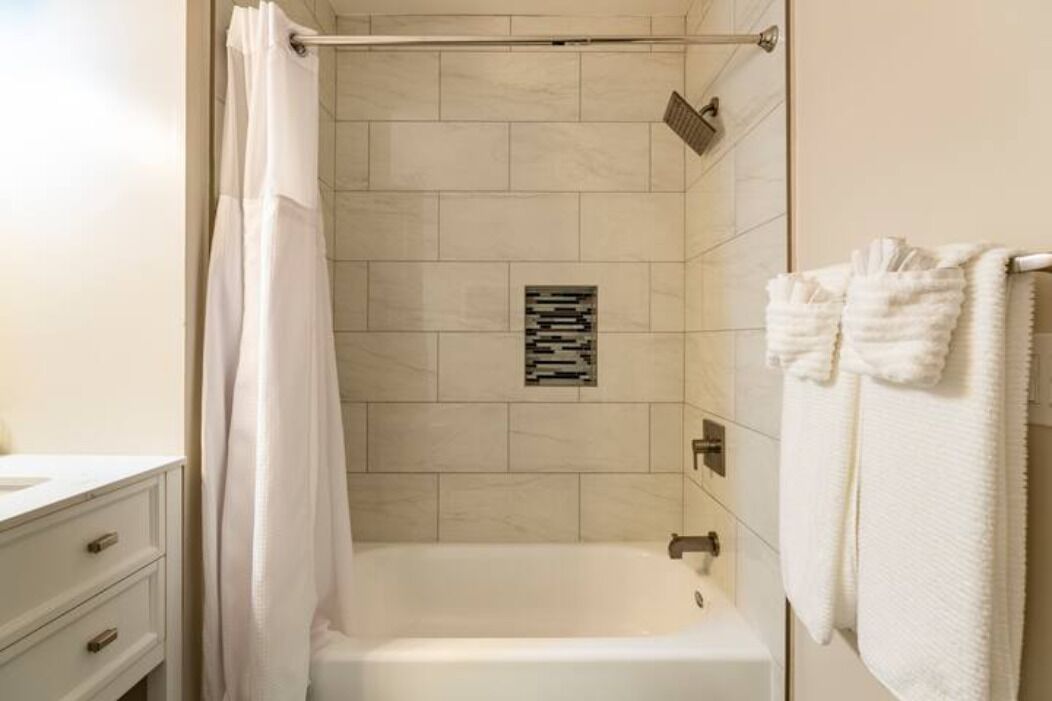 A modern bathroom with a bathtub, a shower, and a towel rack.