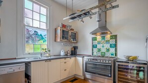 A kitchen with white cabinets, a dishwasher, a stove, and a wine cooler. - Pet-Friendly Blue Mountains Cottage with Indoor Fireplace (Mount Victoria)
