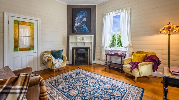 A cozy living room with a fireplace, a large rug, and two armchairs. - Pet-Friendly Blue Mountains Cottage with Indoor Fireplace (Mount Victoria)