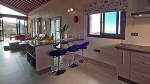 A modern kitchen with a central island, bar stools, and a large window.