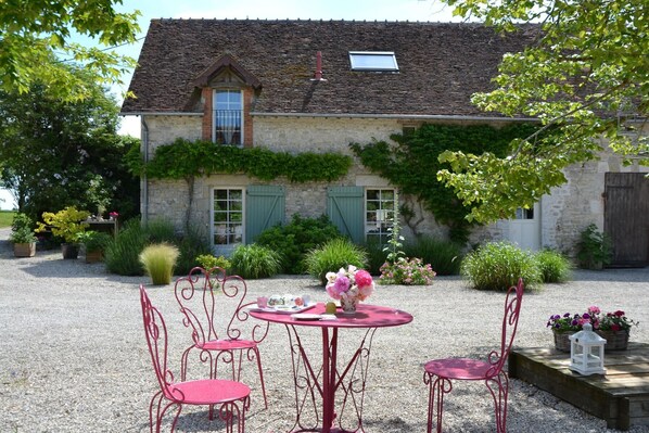 Surrounded by lush greenery, this charming building offers a serene setting with a round table and comfortable seating for four.