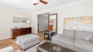 A modern living room with a grey sofa, a coffee table, a wooden cabinet, and a ceiling fan. - Classic style home with a laid-back feel and required amenities for comfort.  (vestavia hills)