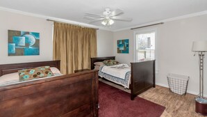 A bedroom with two wooden beds, a ceiling fan, a window with blinds, and abstract wall art. - Classic style home with a laid-back feel and required amenities for comfort.  (vestavia hills)