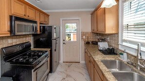 A kitchen with wooden cabinets, stainless steel appliances, a marble floor, and a window with blinds. - Classic style home with a laid-back feel and required amenities for comfort.  (vestavia hills)