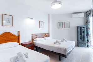 Habitación de hotel con dos camas, una mesita de noche, un armario y cuadros en la pared.