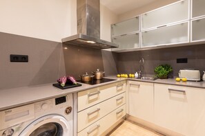 A compact kitchen with a washing machine, a stove, and a sink.