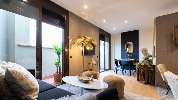 Una sala de estar moderna con un sofá, una mesa de centro y una zona de comedor con sillas y una mesa.