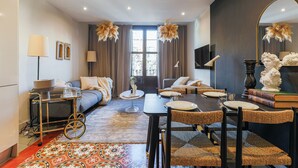 Una sala de estar moderna con un sofá, una mesa de comedor y sillas, un televisor y objetos decorativos.