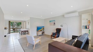 Una sala de estar moderna con una televisión de pantalla plana, un sofá, una mesa de centro y una estantería.