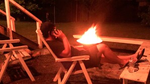 Une personne se détend près d’un feu de camp, la nuit.