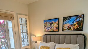 Un dormitorio con una cama, una mesita de noche, una lámpara y dos cuadros en la pared.