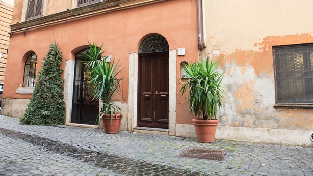 Un bâtiment situé sur une rue pavée, avec une porte marron et des plantes en pot.