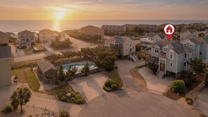 A residential area with houses, a swimming pool, and a view of the ocean at sunset. - Modern Beachhouse, Pool, 73 Steps to Beach, Deck Fully Loaded, Arcade (Nags Head)