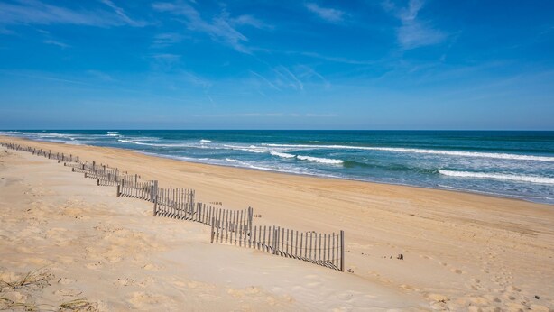 A beach with a wooden fence running parallel to the shoreline. - Modern Beachhouse, Pool, 73 Steps to Beach, Deck Fully Loaded, Arcade (Nags Head)