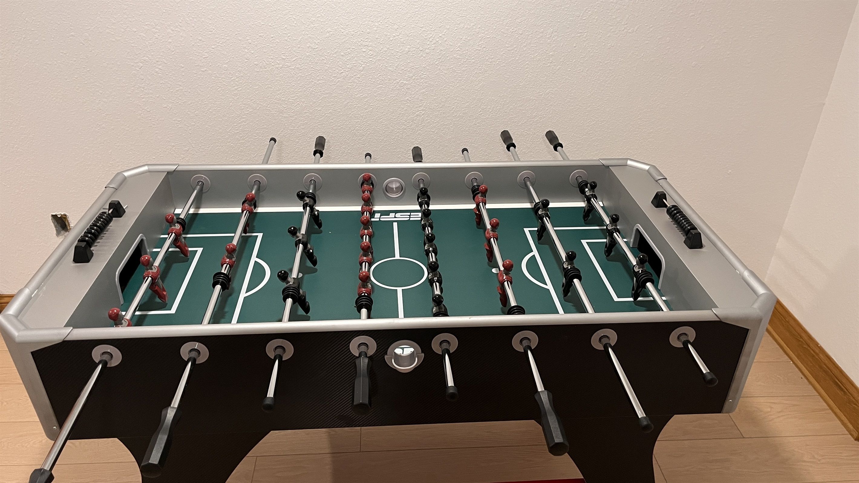 A foosball table with a soccer field layout, including goal areas and player figures.