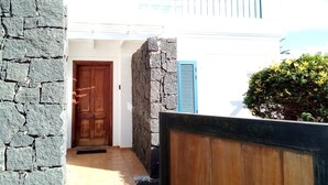 A narrow entrance with a wooden door, stone walls, and a blue shutter. - Beautiful Villa with a private heated pool and roof terrace. (Playa Blanca)